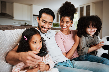 Mom, dad and happy kids on couch, watching tv and family bonding together in living room. Smile, happiness and parents relax with children on sofa, streaming television show subscription or movies., a Photo by Peopleimages.com