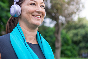 Happy active woman smiling with headphones and towel after outdoor workout