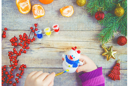 A child paints a Christmas toy, a, a Holiday Photo by yanadjana
