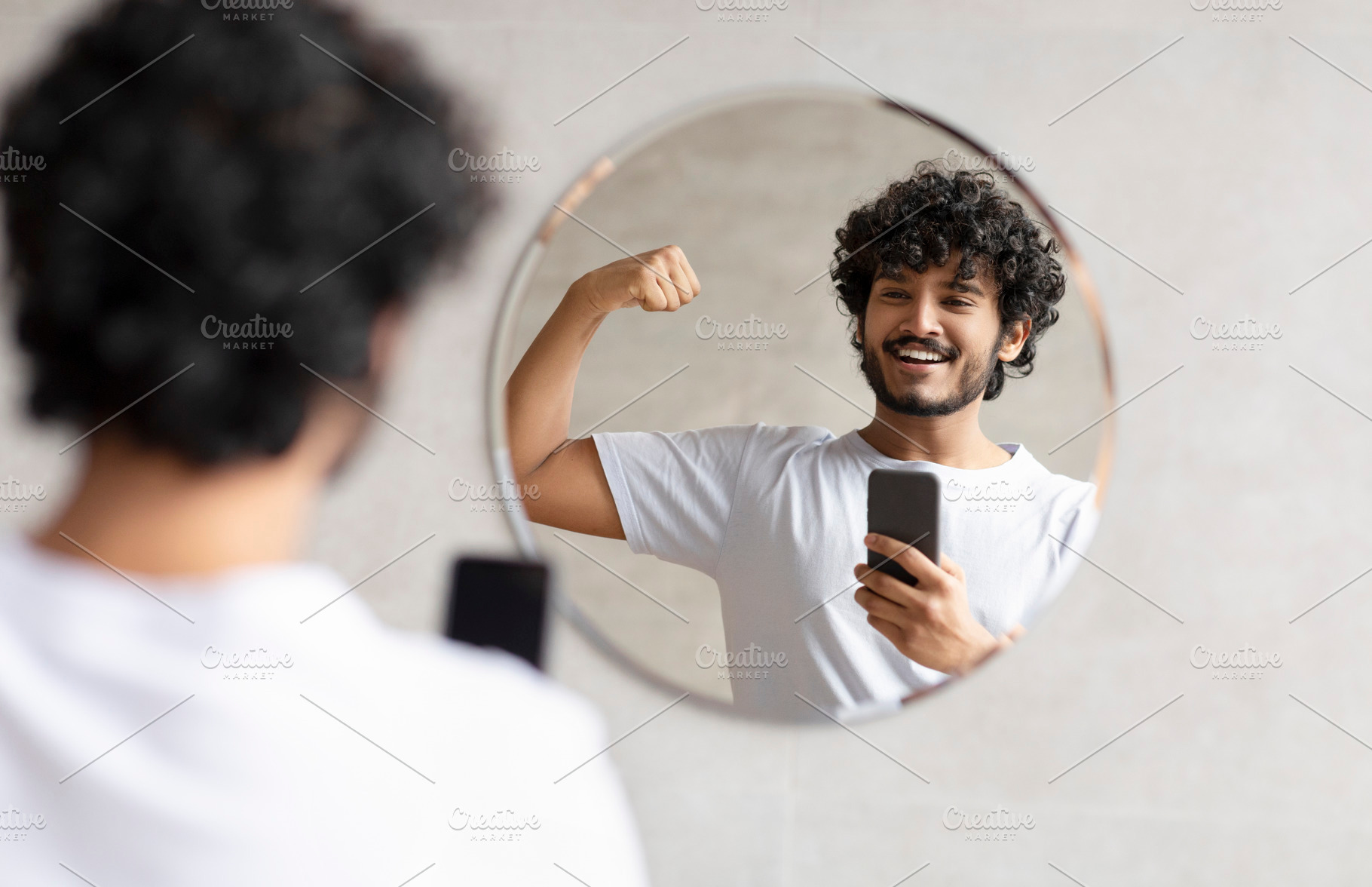 Excited indian man taking photo on smartphone in bathroom mirror, showing perfe, a Person Photo by Prostock-Studio