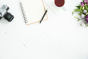 Desk with tea notebook and flowers featuring notebook, tea, and pen