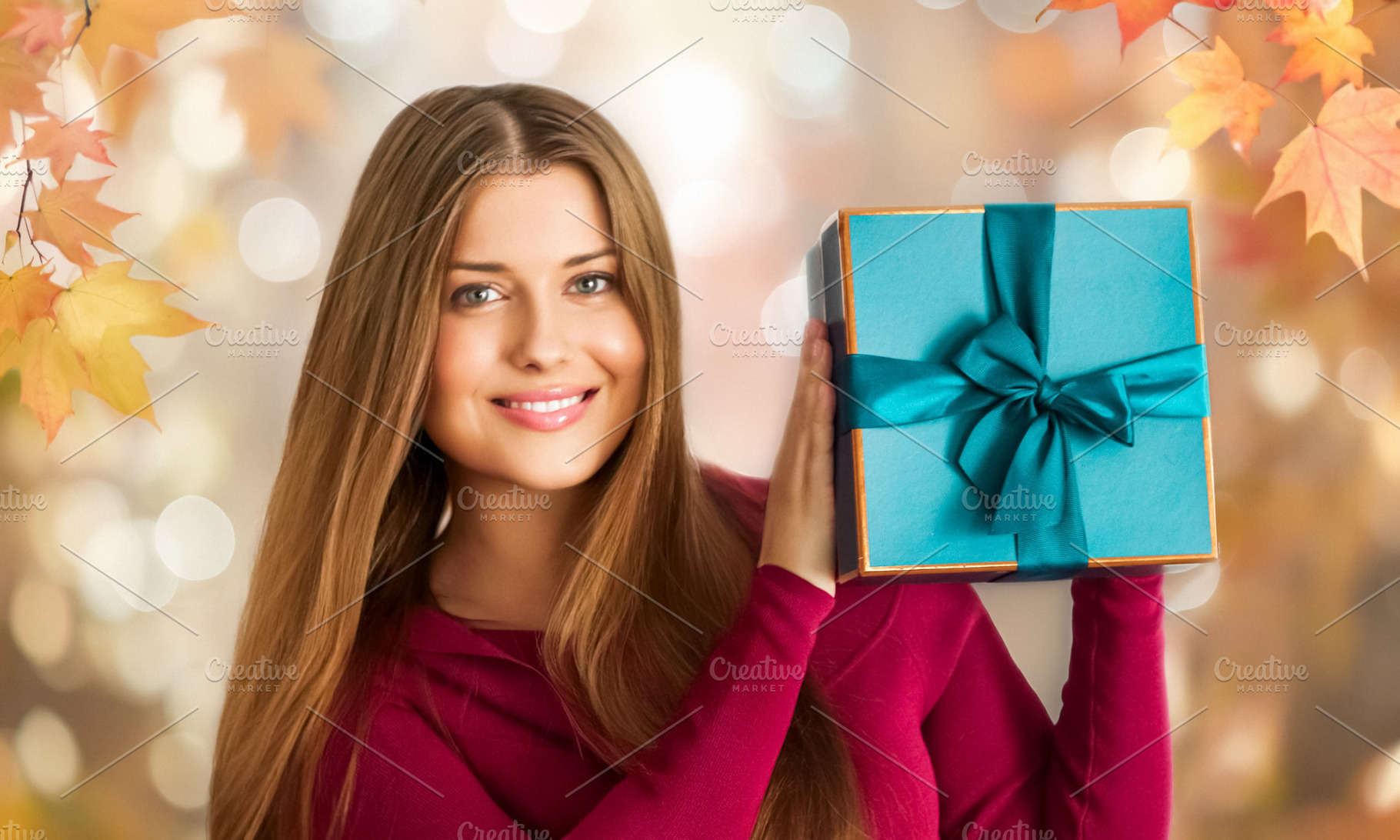 Woman smiling, presenting a beautifully wrapped teal gift box. A, a Person Photo by Studio ANNA