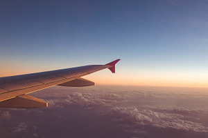 Airplane wing with sunrise featuring above, aircraft, and airplane