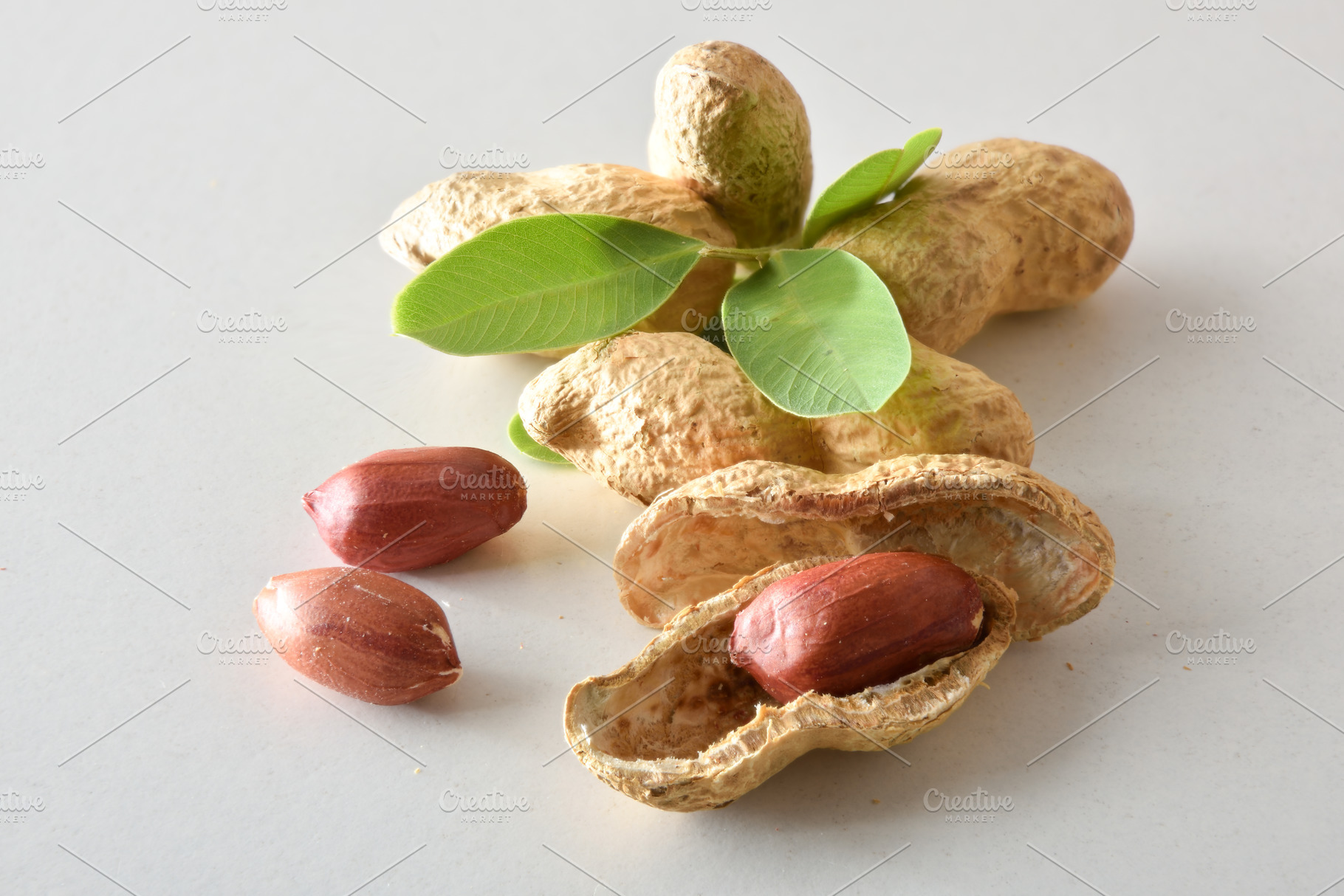Group of peeled and unpeeled peanuts with leaves on table, a Food & Drink Photo by Davizro's Market