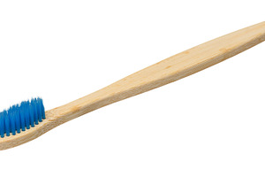 Bamboo toothbrush with blue bristles isolated on background. Clo, a Health & Medical Photo by ndanko
