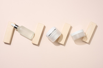 plastic jar and white glass bottle with pipette stands on a beig, a Beauty & Fashion Photo by ndanko