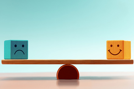 Balancing emotions shown with happy and sad blocks on a Balance