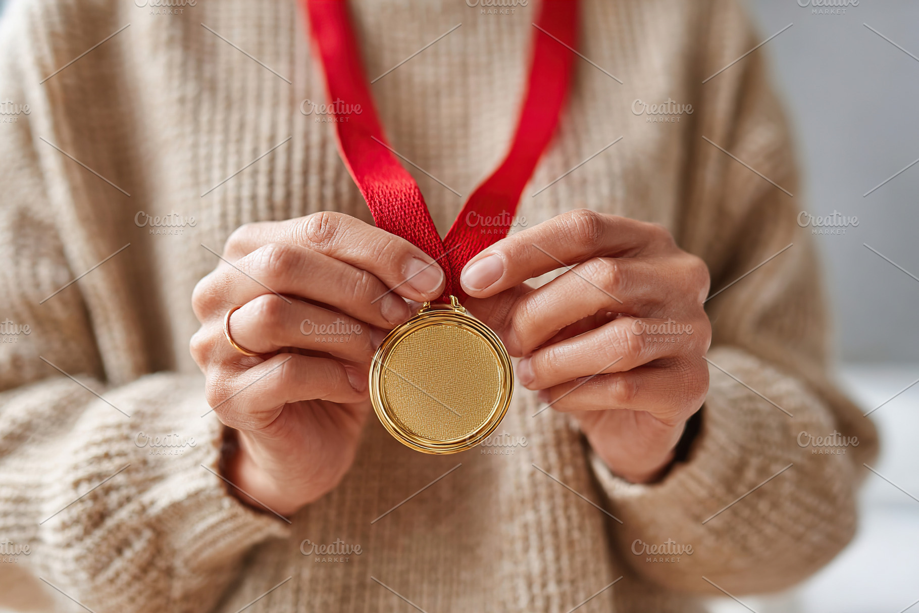 Golden medal with red ribbon held proudly by an individual celebrating achievem, a Photo by AlyaAnd