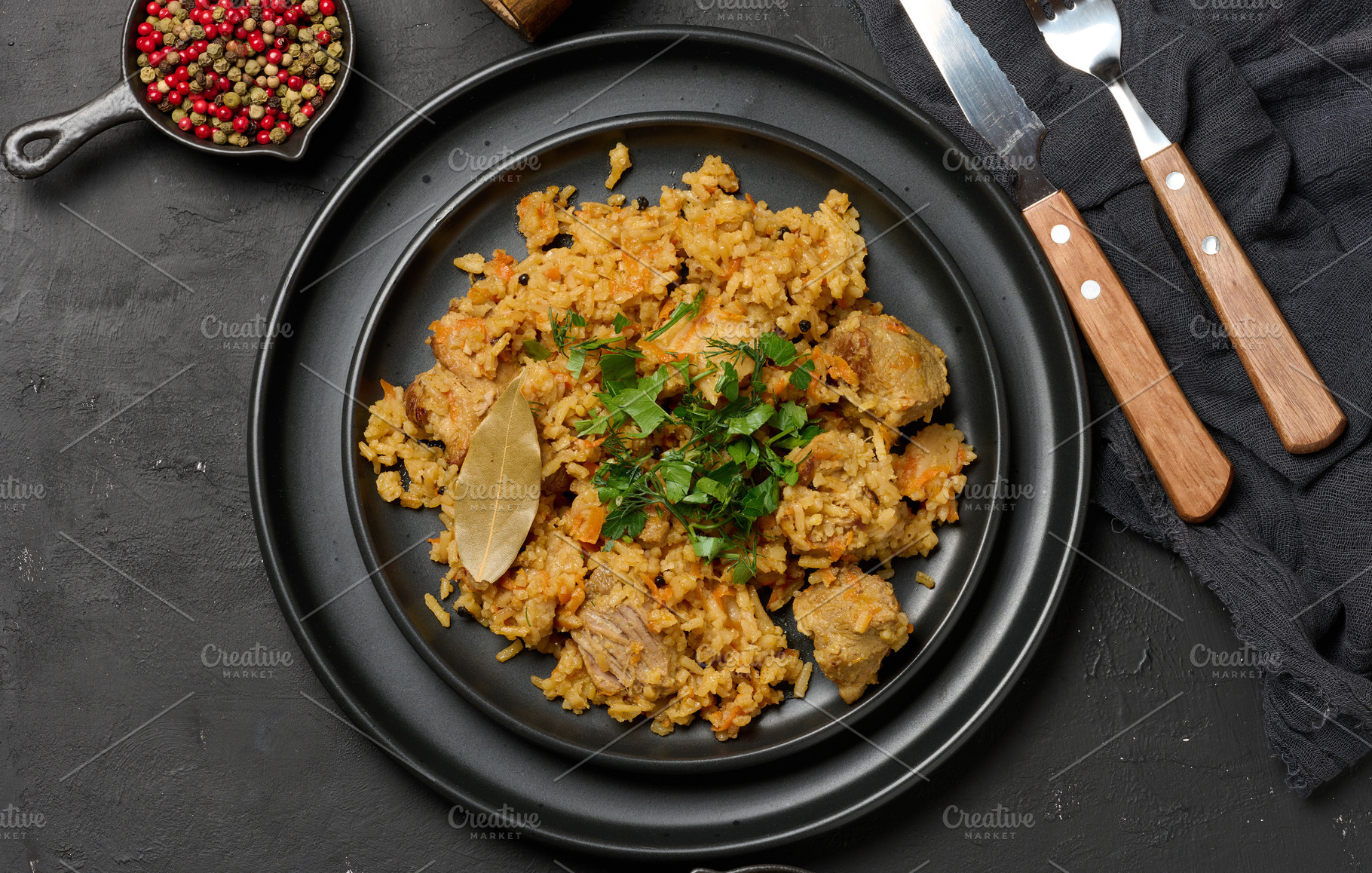 Pilaf with rice and pieces of meat in a black round plate on the, a Food & Drink Photo by ndanko