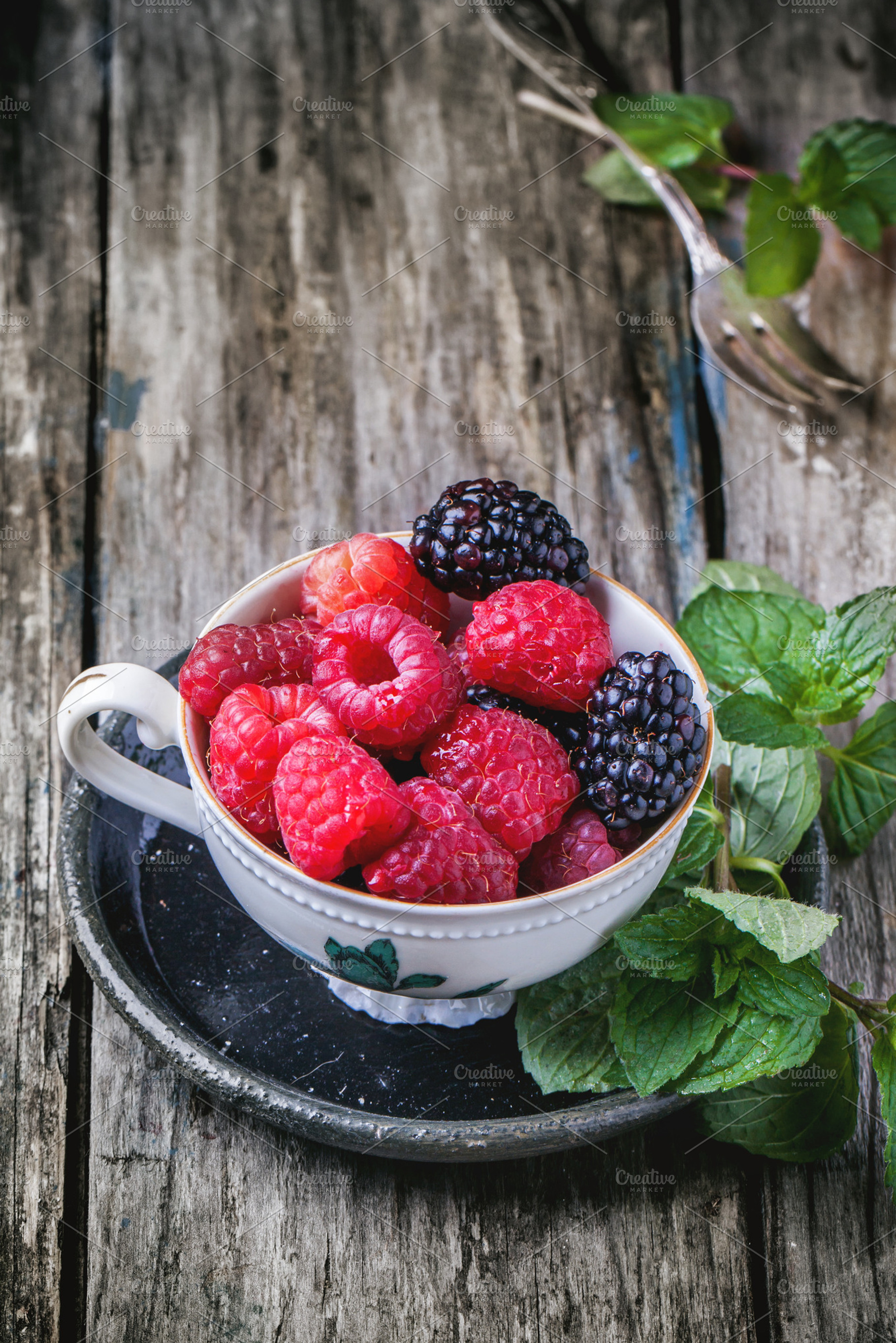 Cup of raspberries and blackberries containing berries, fruit, and wooden
