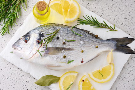 Raw whole dorado fish on white board and spices for cooking, top, a Food & Drink Photo by ndanko