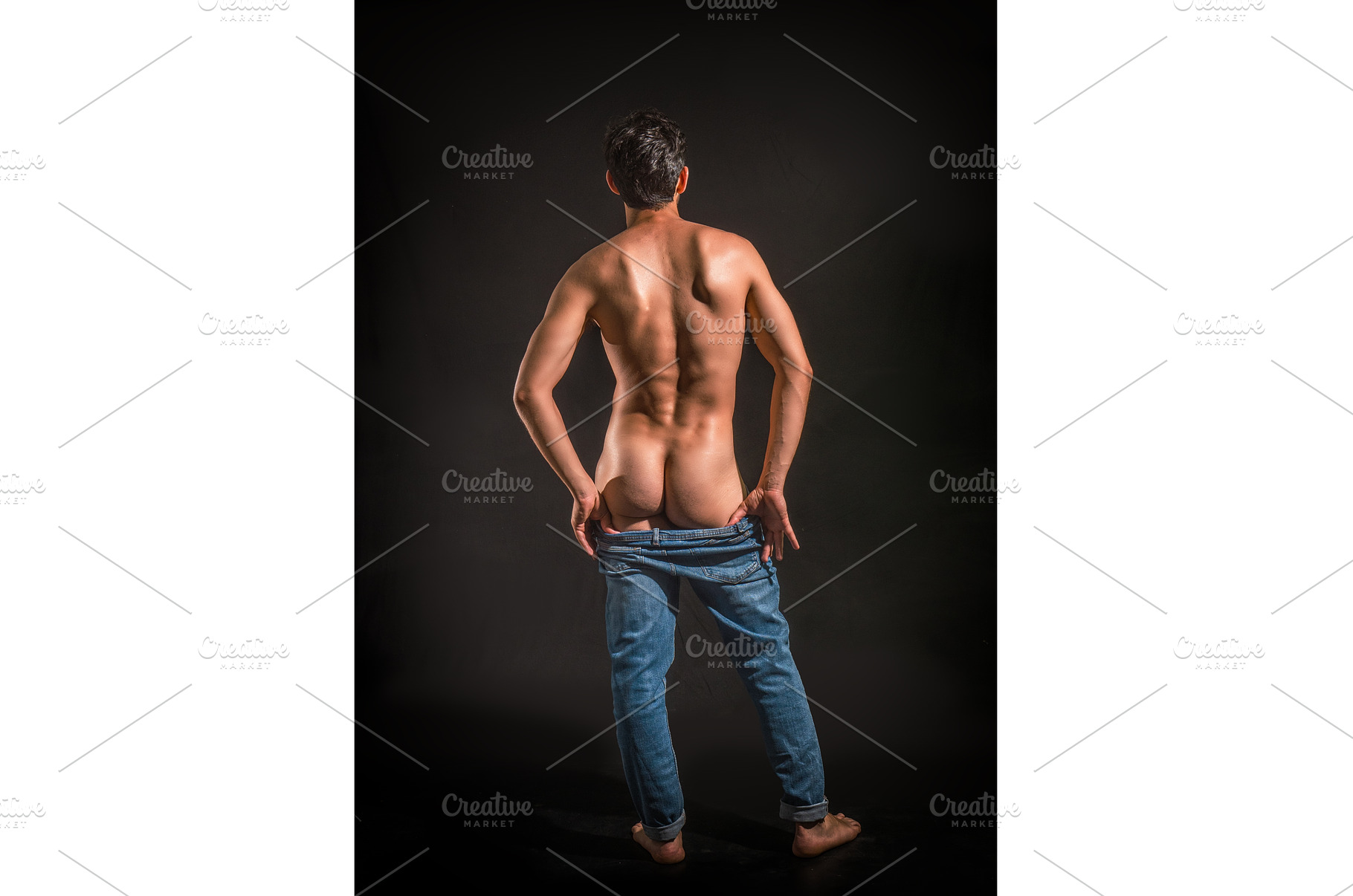 Muscular man pulling down jeans to, a Person Photo by ArtOfPhotos photo store