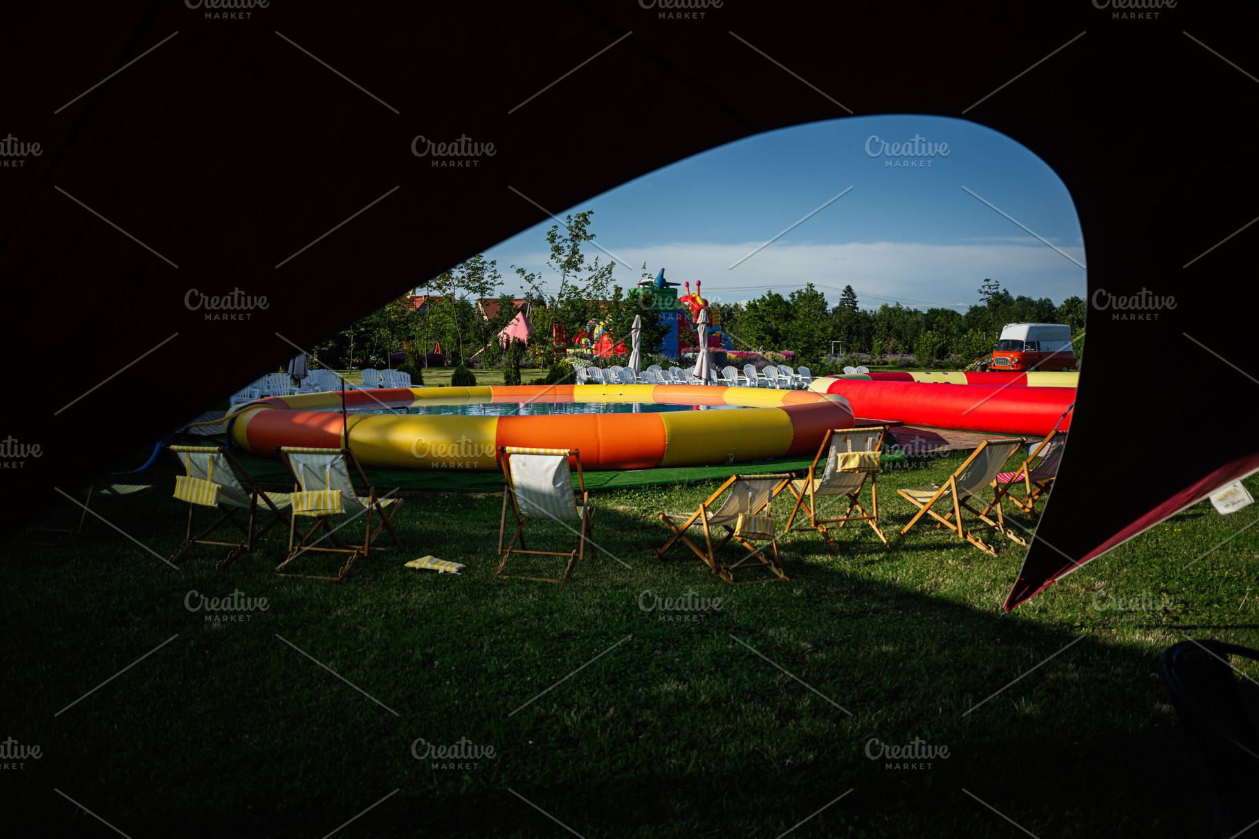 Colorful inflatable structure outdoors surrounded by chairs on green grass, a Photo by AS photostudio