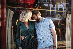 Caucasian couple on streets hugging.