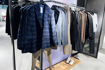 Stylish men's clothing displayed on a rack in a modern retail store, a Photo by AS photostudio
