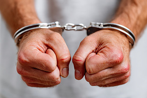 Hands in handcuffs show signs of restraint in an interrogation room setting, a Photo by AlyaAnd