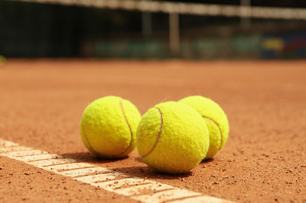 Light green tennis balls on clay court, a Sports & Recreation Photo by AtlasStudio PRO
