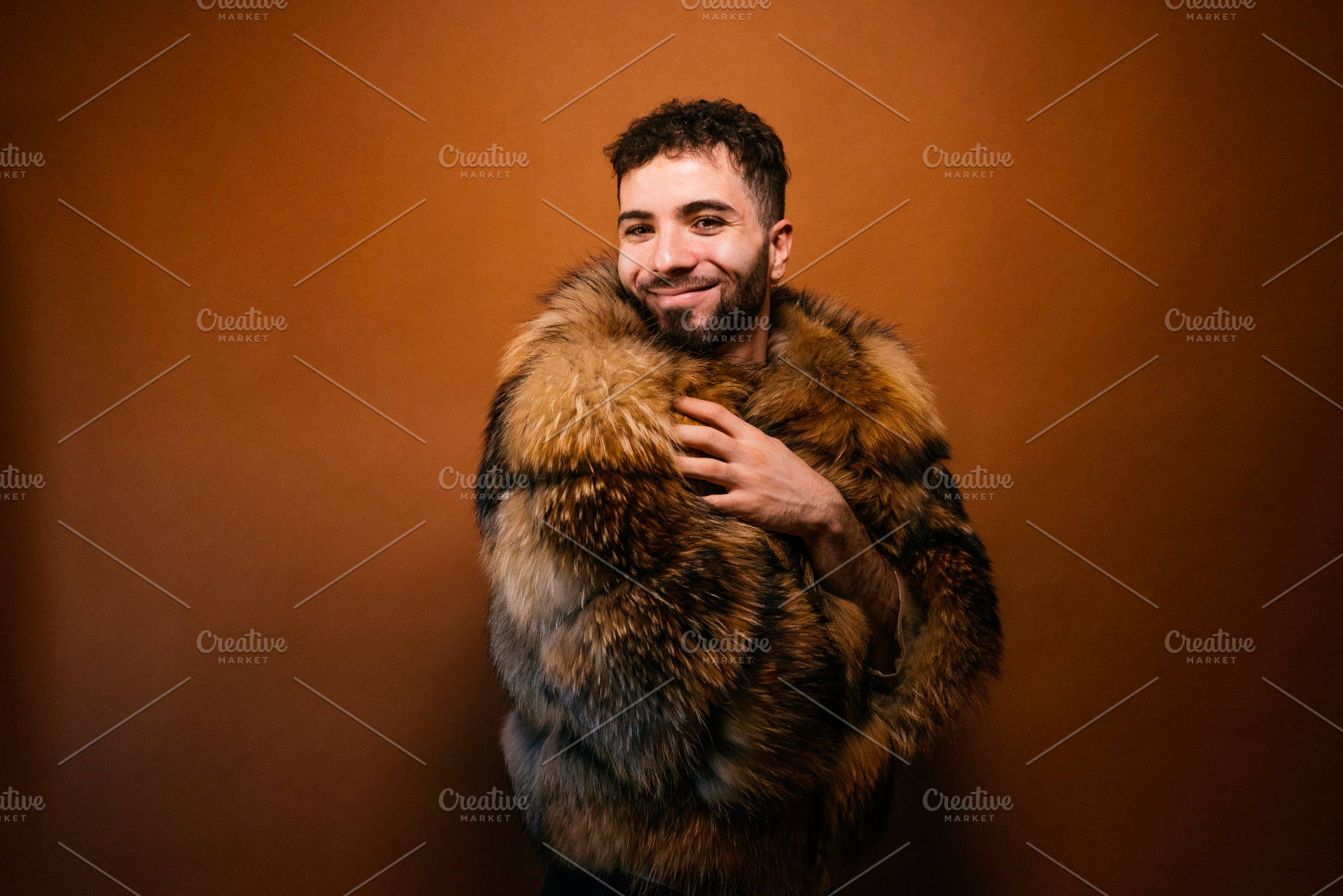 Confident man wearing luxurious faux fur coat smiling, a Photo by karrastock