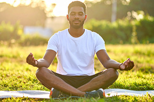 Diverse man meditating outdoors at sunrise, a Health & Medical Photo by DanFLCreativo