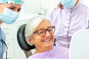 Senior woman admiring her new smile after dental procedure, a Photo by Antonio Gravante Market