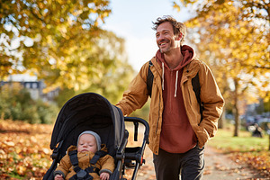 Father enjoys a sunny autumn walk with baby in stroller through park covered in, a Person Photo by AlyaAnd