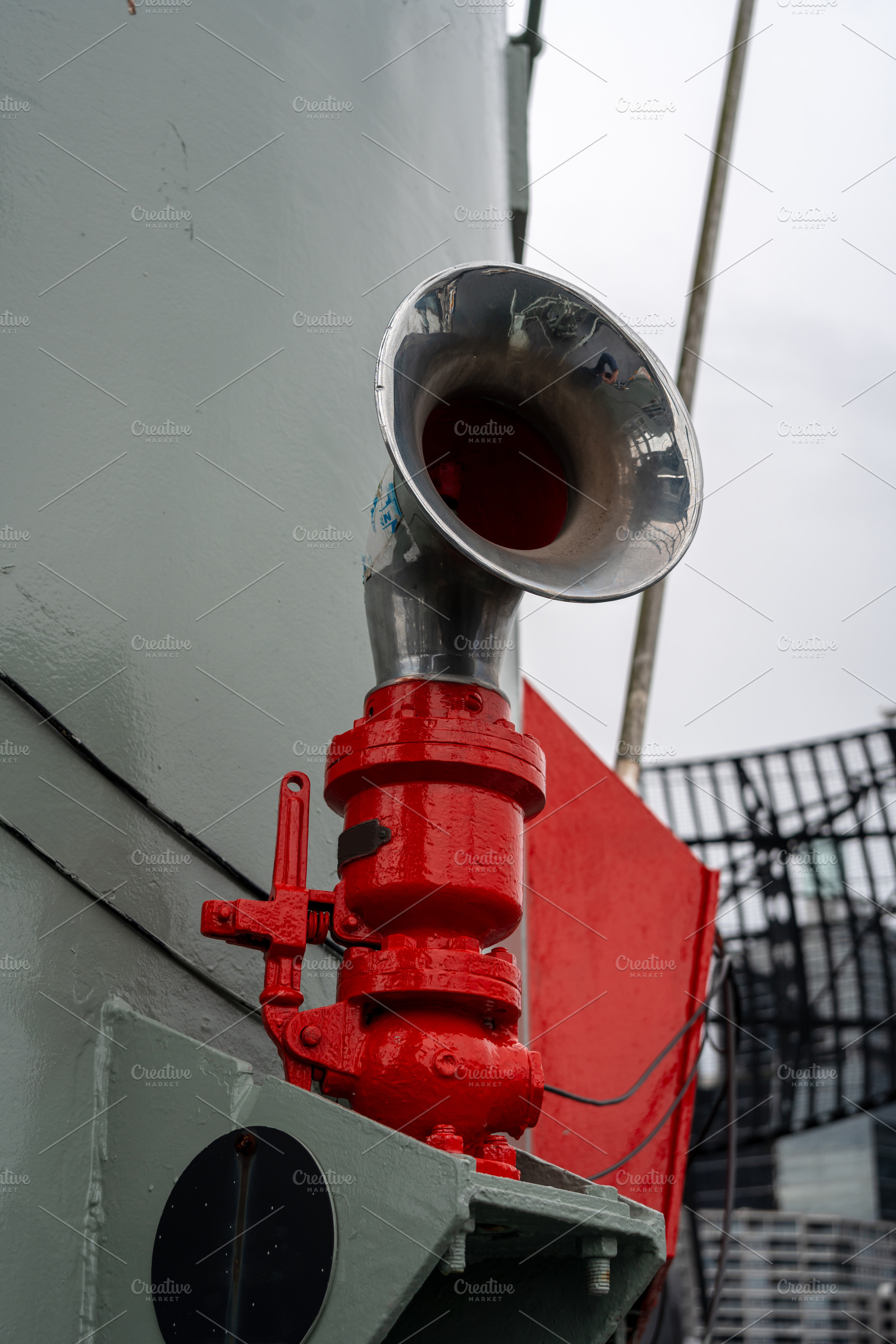 Metal ship horn mounted on a military vessel with red piping, an Architecture Photo by GoodGoods
