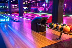 Various bowling balls arranged in stand at illuminated shopping mall, a Photo by andreonegin market