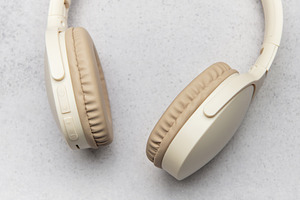 Modern wireless headphones lying on gray stone background, a Business Photo by Olena Rudo
