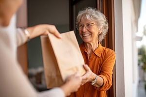 Elderly woman receiving a delivery with a smile, a Person Photo by AlyaAnd