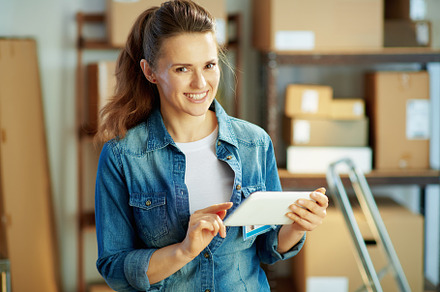 smiling woman in jeans in office using tablet PC applications, a Person Photo by Alliance Images