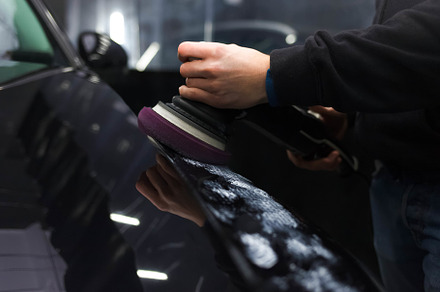 Worker polishes a car’s paintwork, a Photo by borodai94