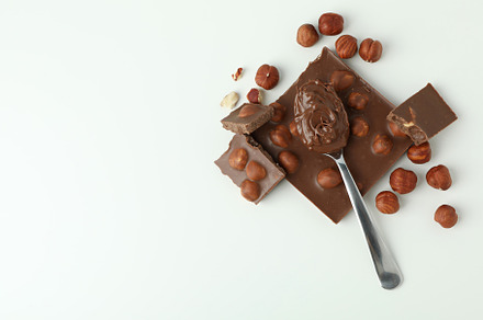 Spoon with chocolate paste and chocolate with nuts on white back, a Food & Drink Photo by AtlasStudio PRO
