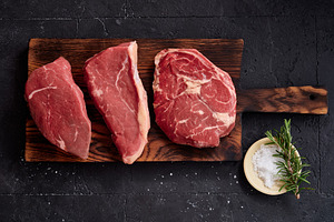 Raw rib-eye, roast beef, flank and rump steak are displayed on a wooden cutting, a Food & Drink Photo by Asya Nurullina