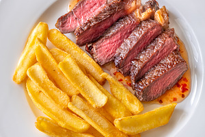 Sliced grilled beef steak with fries, a Food & Drink Photo by Alexander Prokopenko