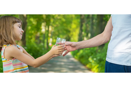 The father gives the child a glass, a Food & Drink Photo by yanadjana