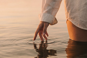 Woman touching calm lake water, a Beauty & Fashion Photo by Virgo Studio