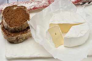 Sliced round head of Camembert cheese on a white board, a Food & Drink Photo by ndanko