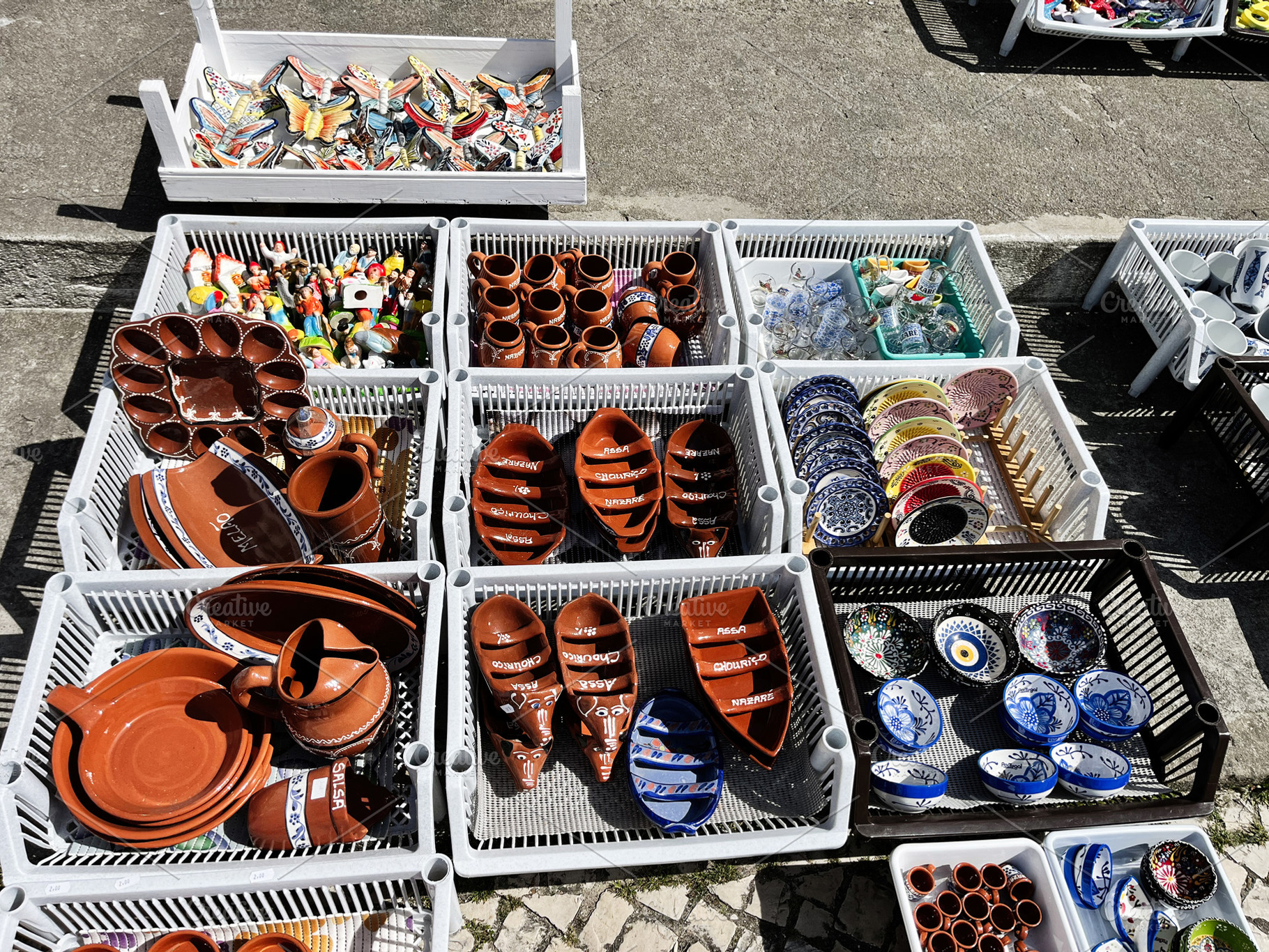 Handcrafted pottery and souvenirs displayed at a market in Nazare, Portugal, a Photo by AS photostudio