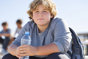 Thoughtful overweight boy on bleachers with drink, a Person Photo by AlyaAnd