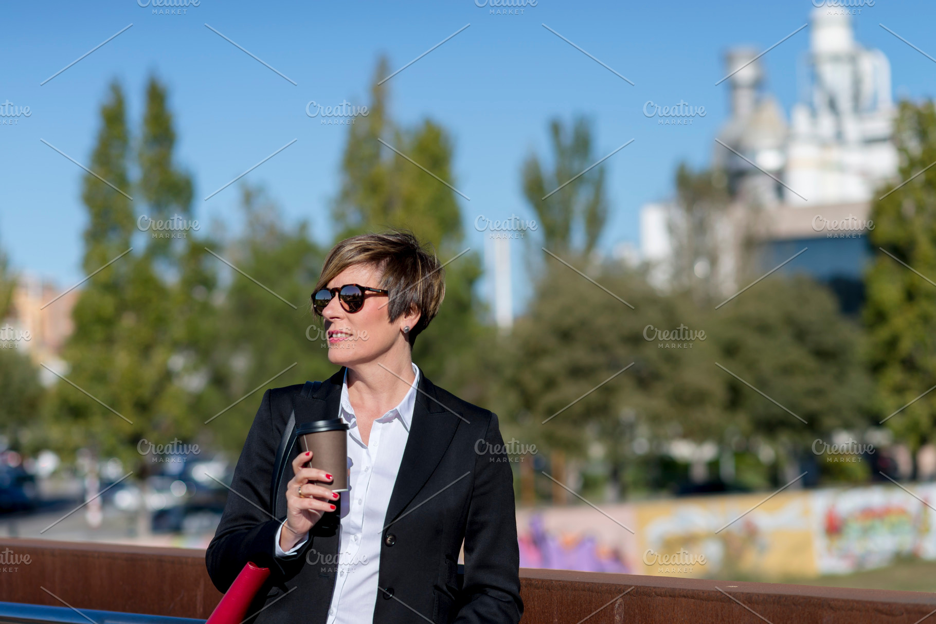 Businesswoman with coffee standing in city park, a Photo by RF Images