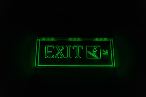 Bright green exit sign glowing in darkness, highlighting emergency stairs for s, an Abstract Photo by Ales Munt