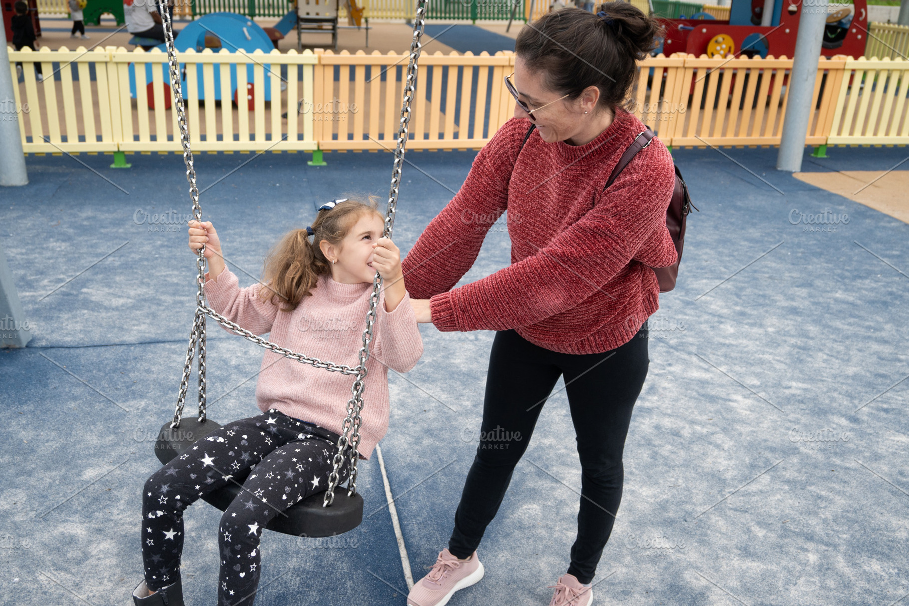 Mother pushing her daughter on a swing at a playground, a Person Photo by etorres69