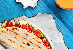 Piadina with grilled zucchini and tomatoes served with orange juice for a vegan, a Food & Drink Photo by Antonio Gravante Market