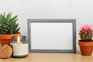Empty frame, burning candle and succulents creating cozy home at, a Background Photo by Olena Rudo
