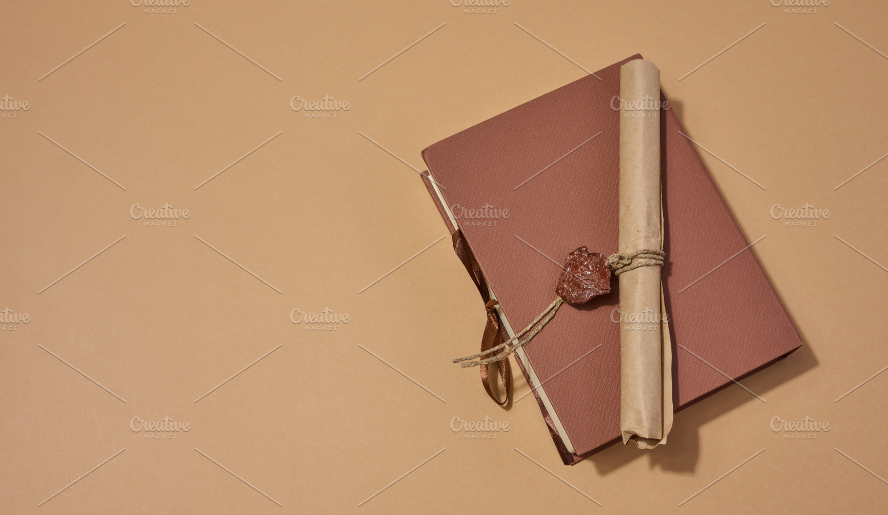 A closed book with a sealed scroll lying on top, on a neutral ba, an Abstract Photo by ndanko