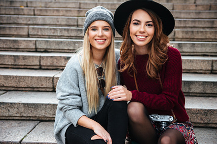 Portrait of two smiling cheerful girls sitting on a staircase, a Person Photo by Dean Drobot