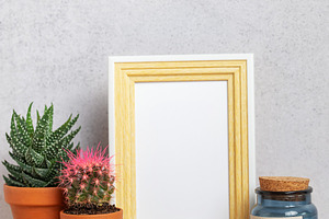 Empty photo frame with cacti, candle and copy space on wooden ta, a Business Photo by Olena Rudo