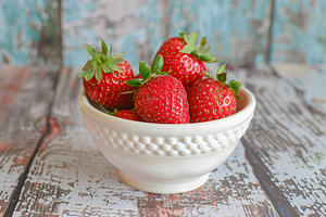 Red strawberries in bowl on wooden table, a Food & Drink Photo by AlyaAnd