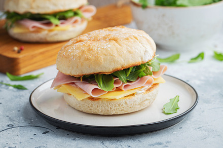 Two homemade sandwiches with ham, cheese and arugula on a concrete table., a Food & Drink Photo by Budarinphoto