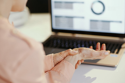 Closeup on stressed modern woman with laptop having wrist pain, a Business Photo by Alliance Images